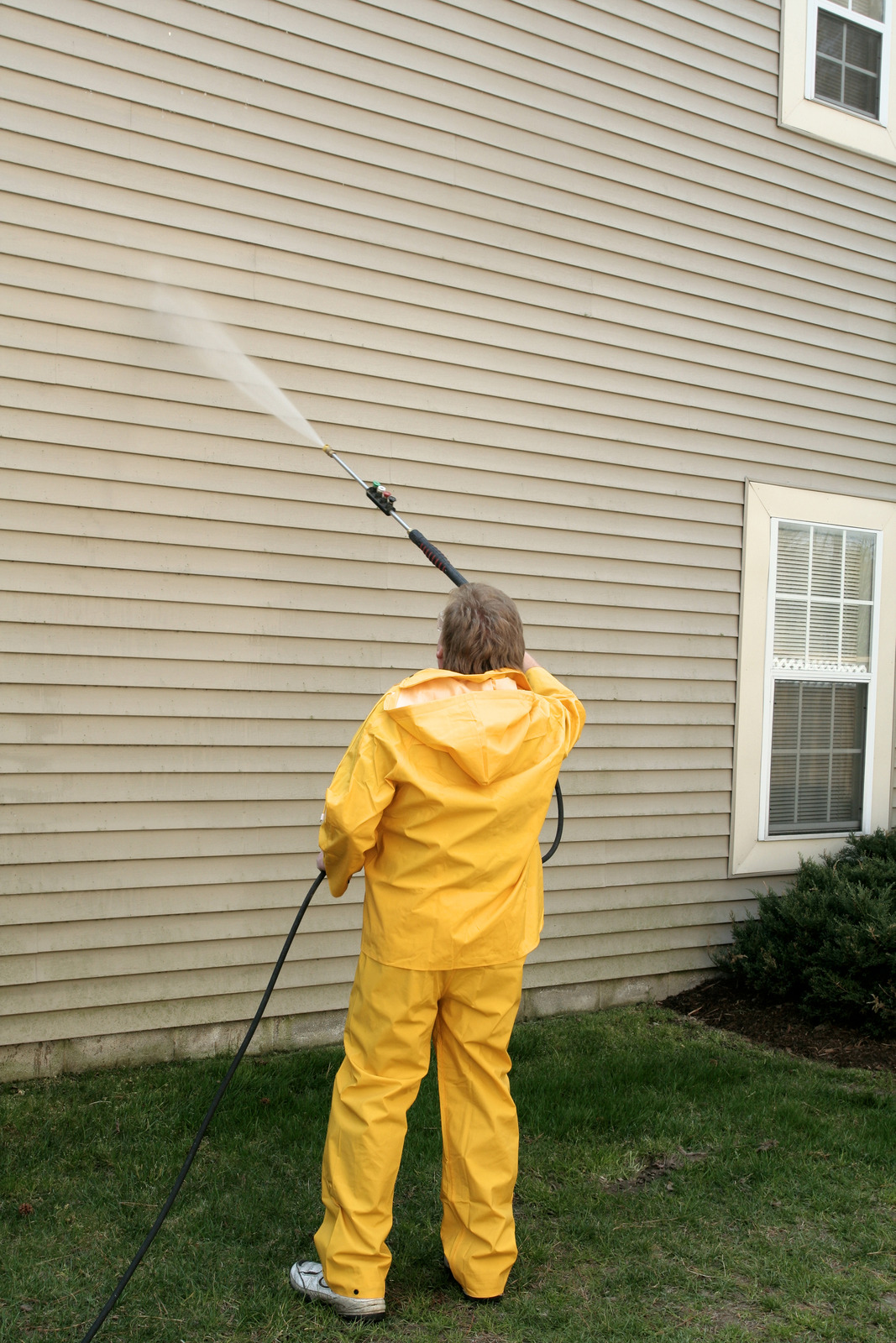 Technician soft washing a home exterior