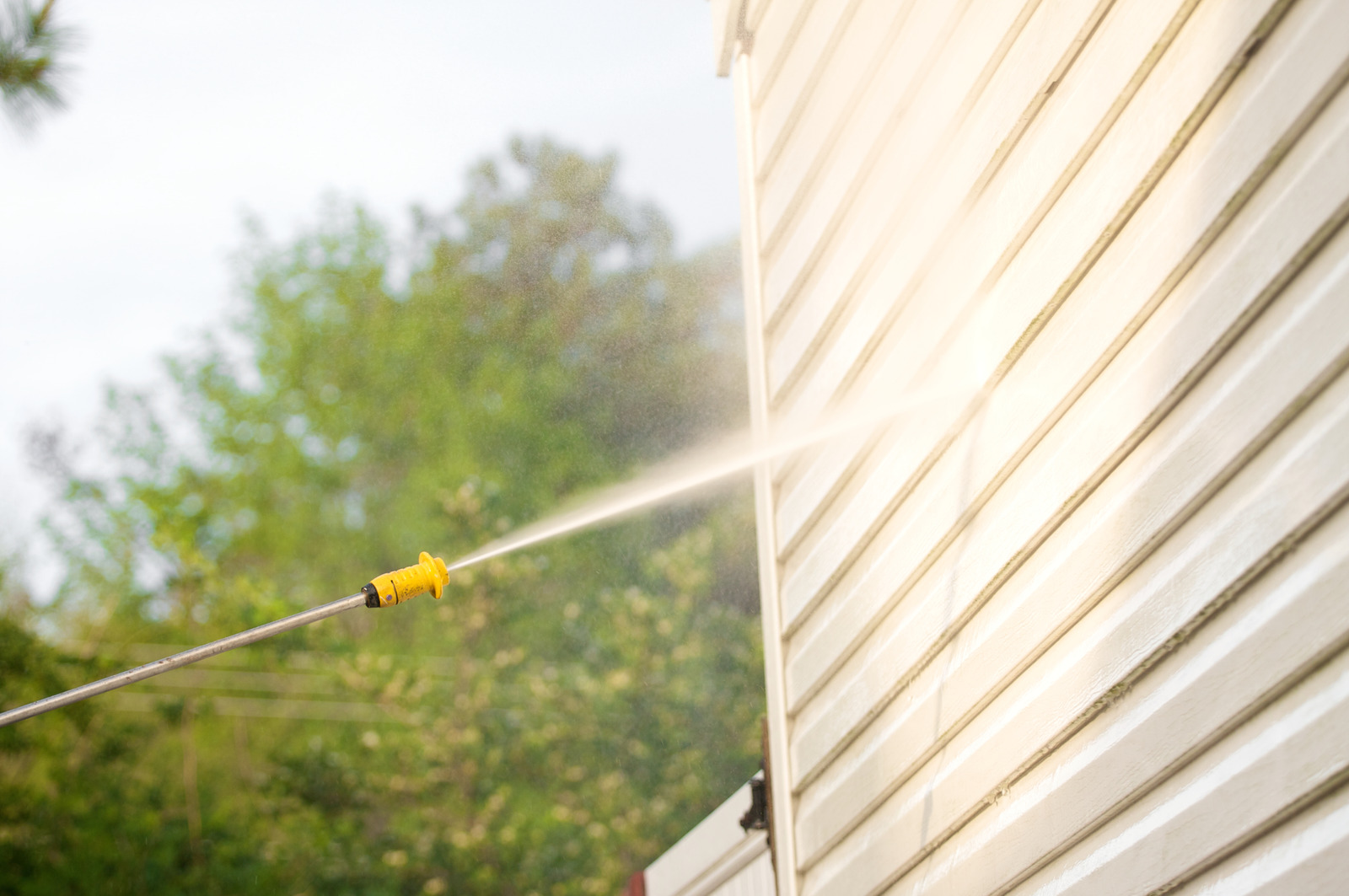 Exterior siding being cleaned with a softwash method