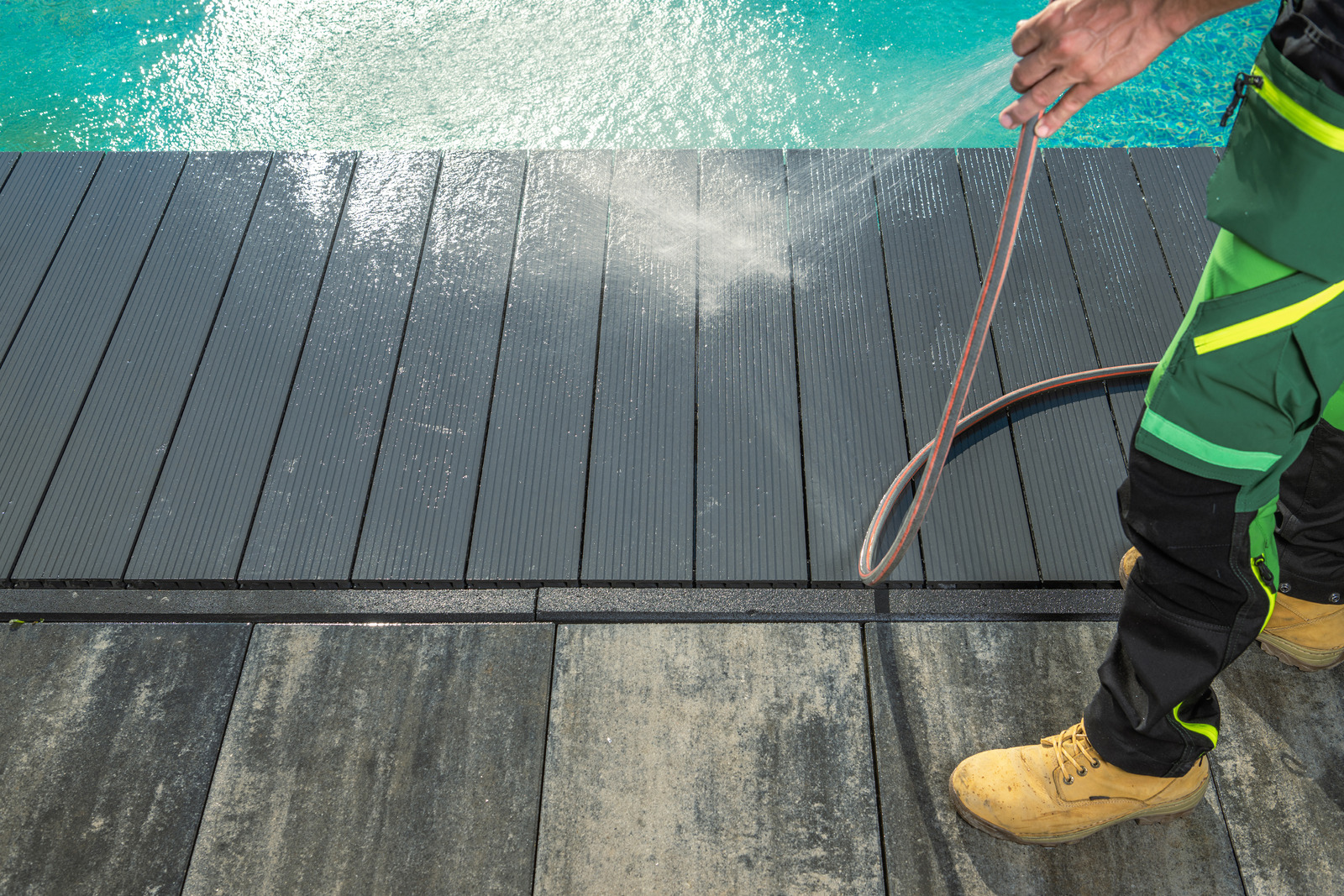 Pool deck surface being cleaned with low-pressure spray